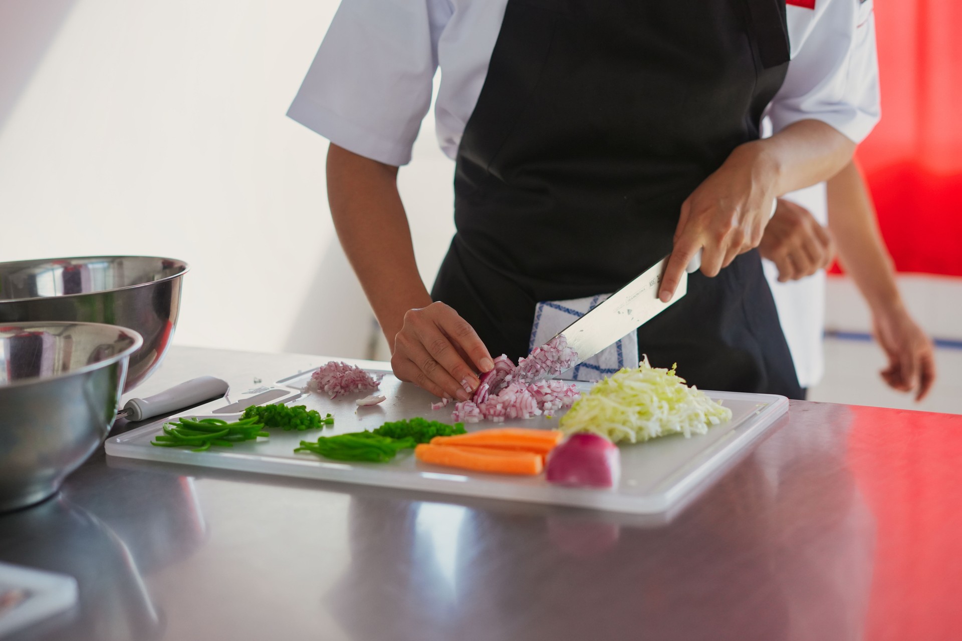 Chef chopping fresh vegetables on cutting board in kitchen